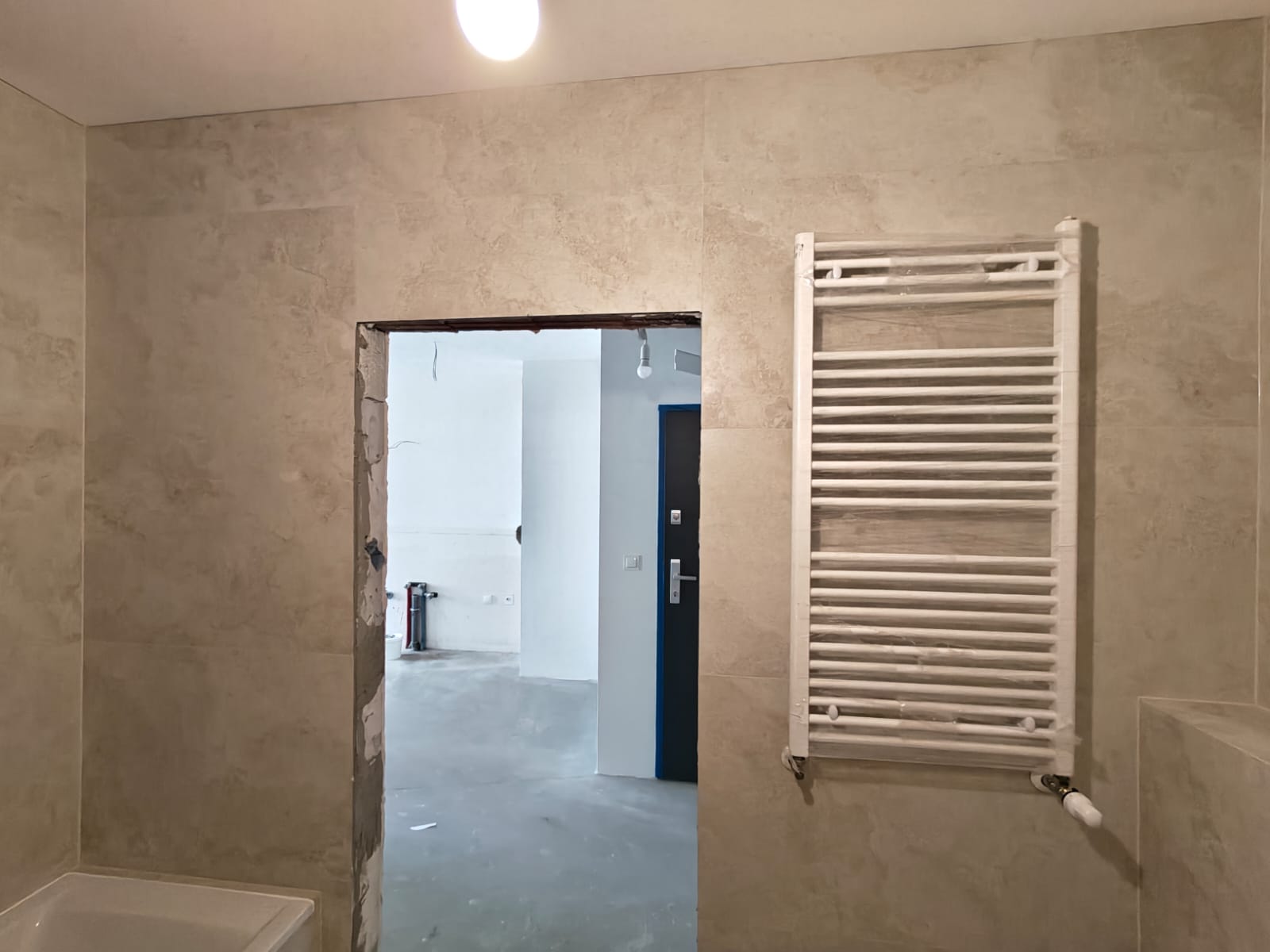 Remont łazienki, realizacja AquaMaster — grzejnik drabinkowy i wanna w obudowie z trawertynu