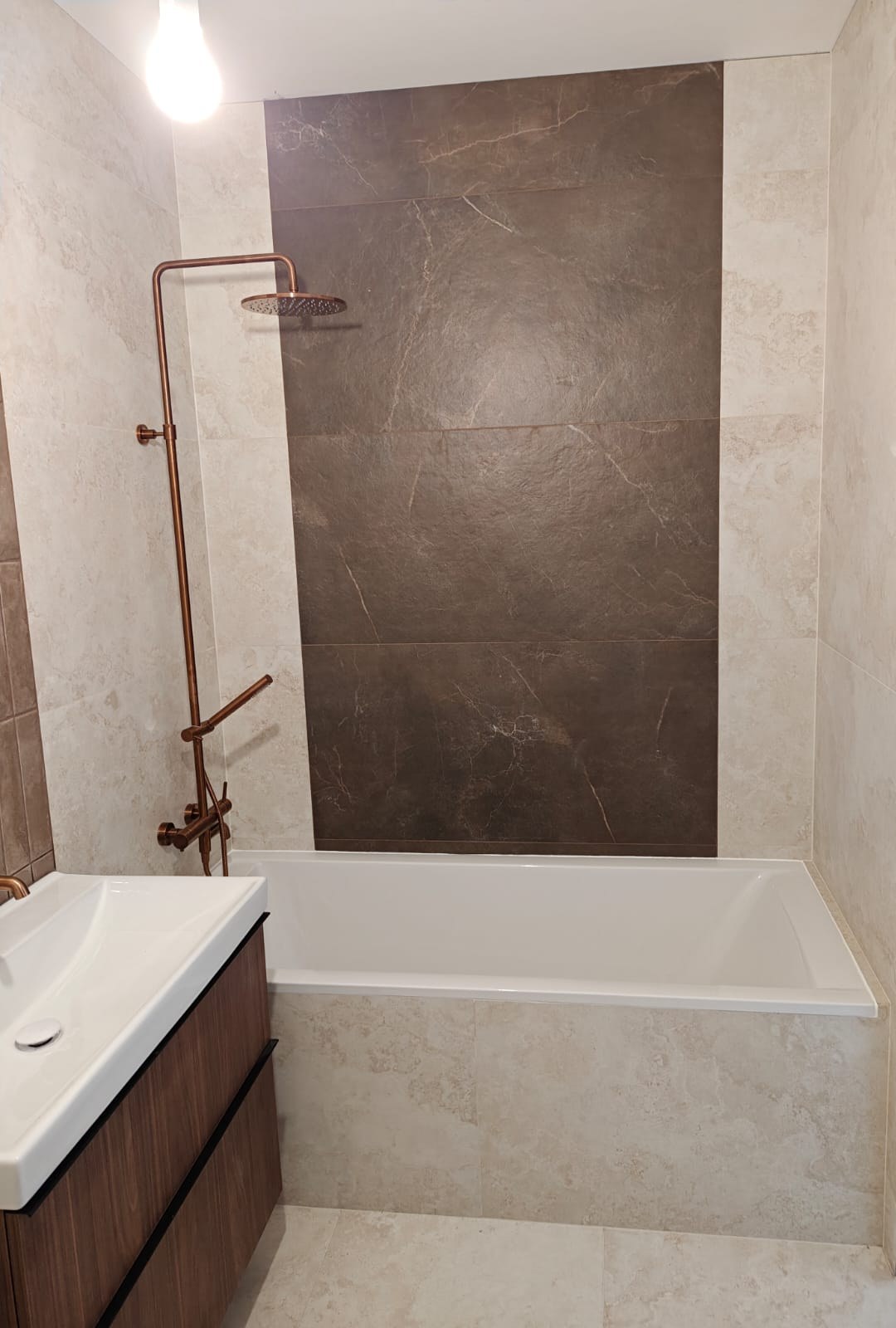 Remont łazienki, realizacja AquaMaster — wanna z deszczownicą w kolorze miedzi i ciemną ścianą