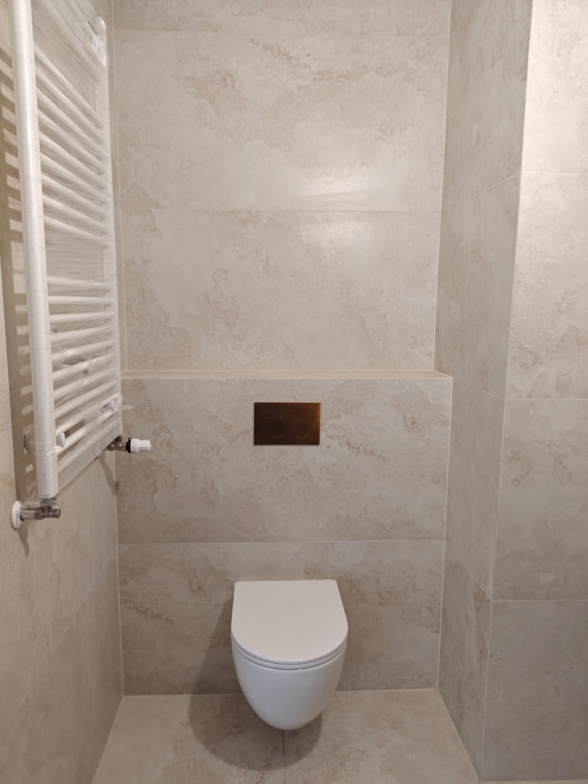 Remont łazienki, realizacja AquaMaster — wiszące WC, grzejnik i wielkoformatowy trawertyn
